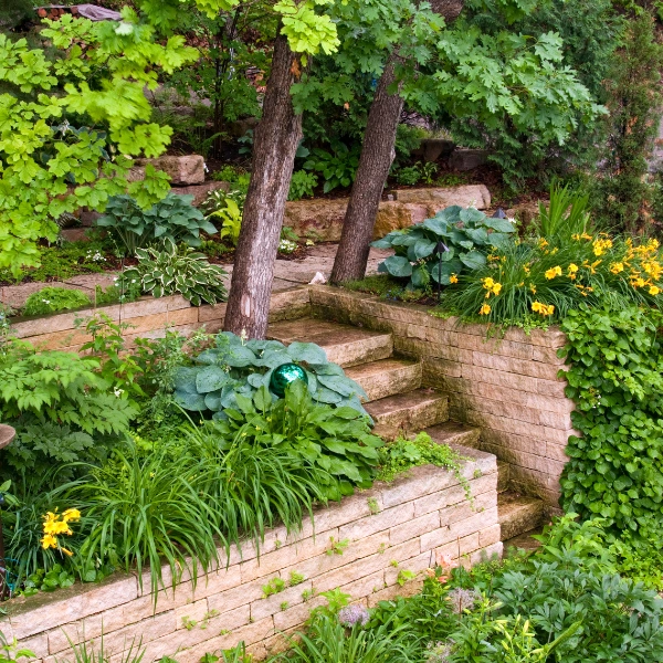 A photograph showing a sturdy retaining wall made from concrete blocks in a garden setting.